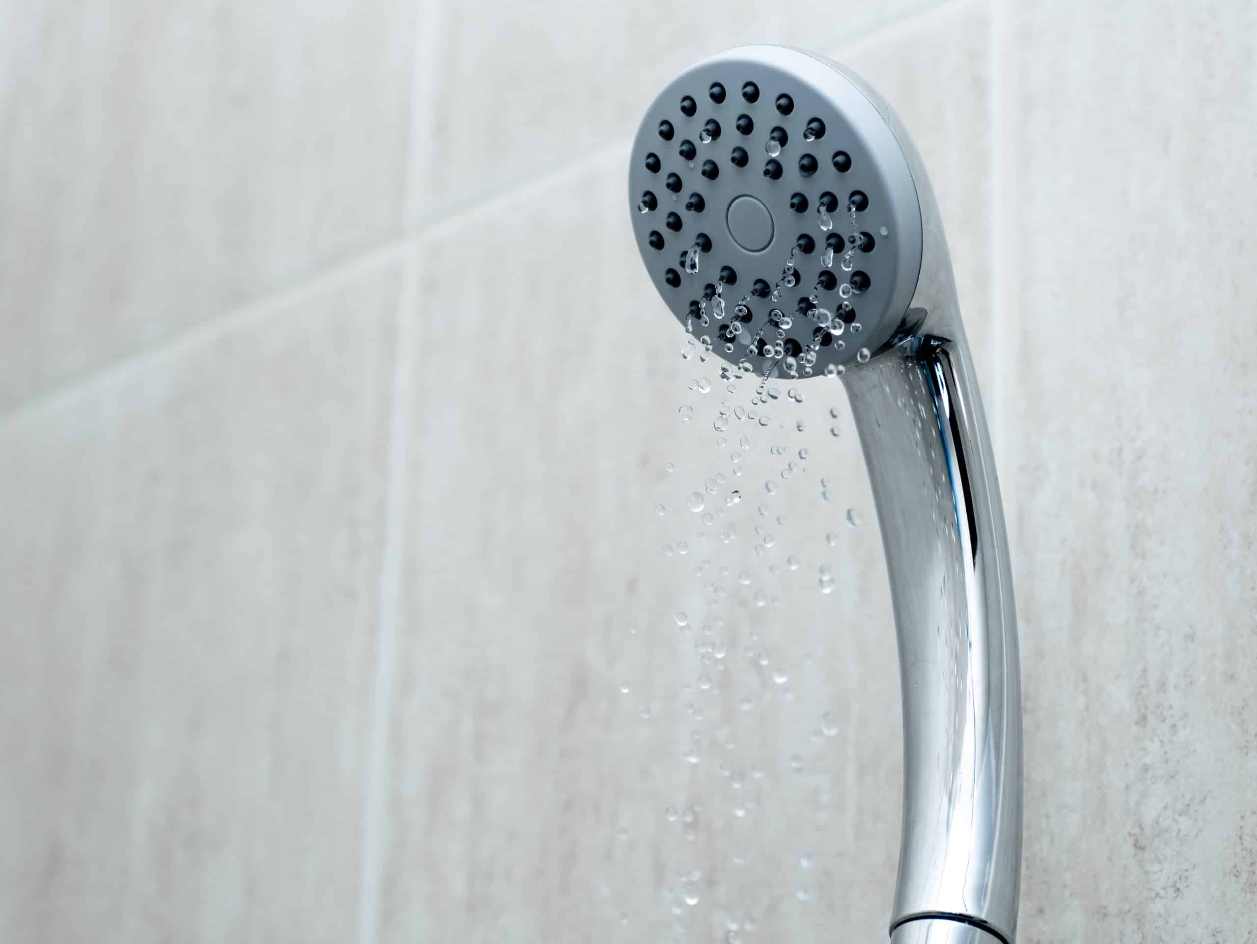 A shower head with a trickling water stream due to low water pressure