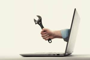 A plumber's hand holding a wrench, reaching out of a laptop screen